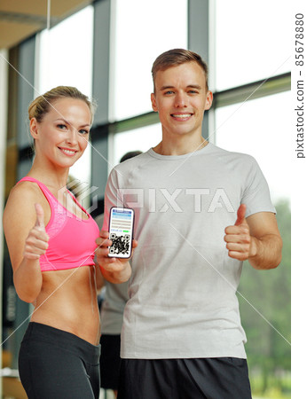 happy couple with qr code on smartphone in gym 85678880