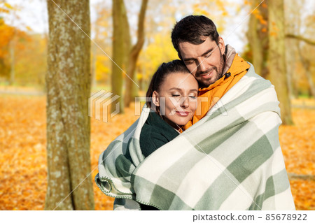 happy couple in warm blanket over autumn park happy couple in warm blanket over autumn park 85678922