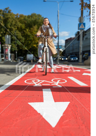 woman cycling along red bike lane road in city woman cycling along red bike lane road in city 85678934