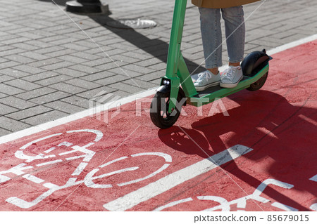 woman riding scooter along bike lane road in city 85679015