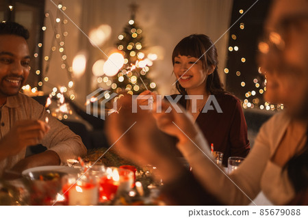 happy friends with sparklers at christmas dinner happy friends with sparklers at christmas dinner 85679088