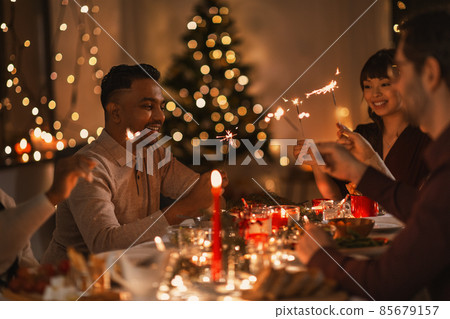 happy friends with sparklers at christmas dinner 85679157