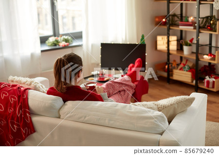 woman watching tv and drinking coffee on christmas woman watching tv and drinking coffee on christmas 85679240