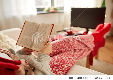 young woman reading book at home on christmas young woman reading book at home on christmas 85679245