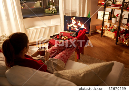 woman watching tv and drinking coffee on christmas 85679269