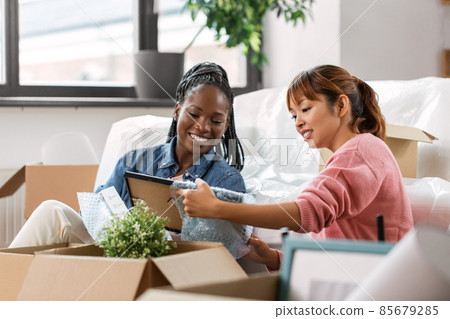 women unpacking boxes and moving to new home women unpacking boxes and moving to new home 85679285