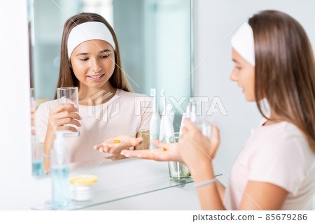 teenage girl taking cod liver oil at mirror 85679286