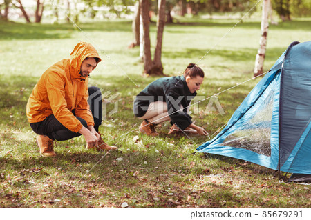 happy couple setting up tent outdoors happy couple setting up tent outdoors 85679291