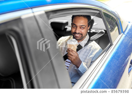 indian man with takeaway coffee on car back seat indian man with takeaway coffee on car back seat 85679398