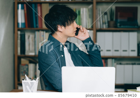 一個男人在工作中打智能手機電話 一個男人在工作中打智能手機電話 85679410