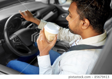 tired indian man or driver with coffee driving car tired indian man or driver with coffee driving car 85679413