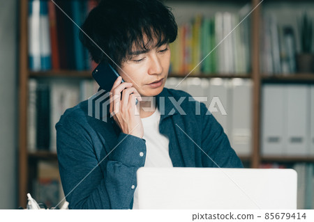 一個男人在工作中打智能手機電話 一個男人在工作中打智能手機電話 85679414