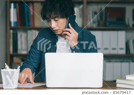 一個男人在工作中打智能手機電話 85679417