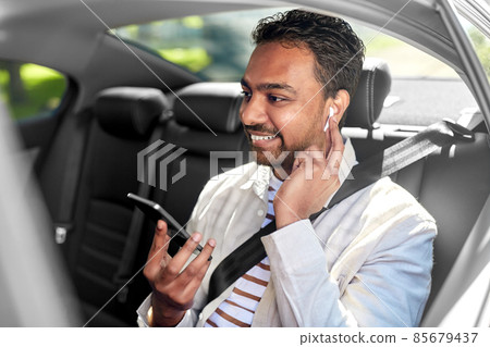 passenger with earphones and cellphone in taxi car 85679437