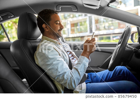smiling indian man in car using smartphone smiling indian man in car using smartphone 85679450