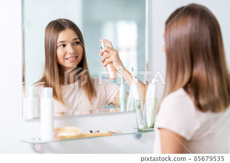teenage girl using hair styling spray at bathroom teenage girl using hair styling spray at bathroom 85679535