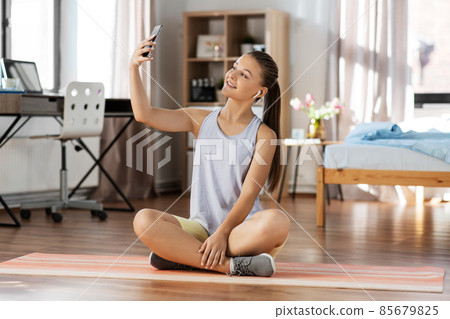girl with phone and earphones takes selfie at home girl with phone and earphones takes selfie at home 85679825