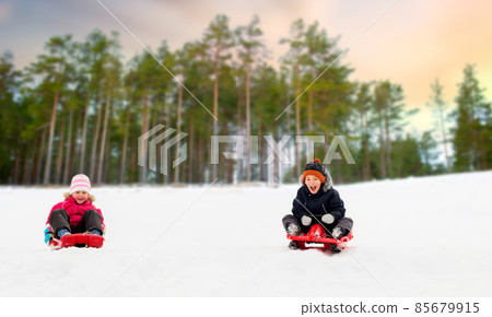kids sliding on sleds down snow hill in winter kids sliding on sleds down snow hill in winter 85679915