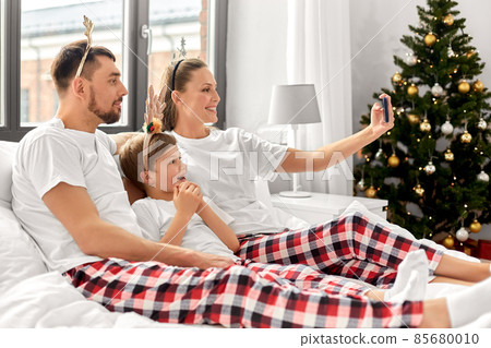 family in pajamas taking christmas selfie in bed family in pajamas taking christmas selfie in bed 85680010