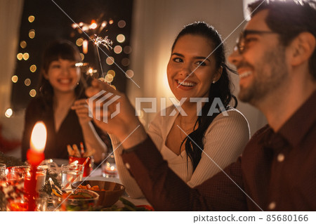 happy friends with sparklers at christmas dinner happy friends with sparklers at christmas dinner 85680166