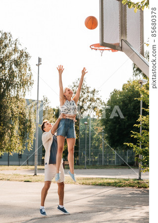 happy couple playing on basketball on playground 85680378