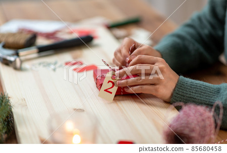 hands packing christmas gift for second advent day 85680458