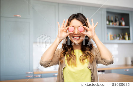 happy woman with eyes of macarons on kitchen 85680625