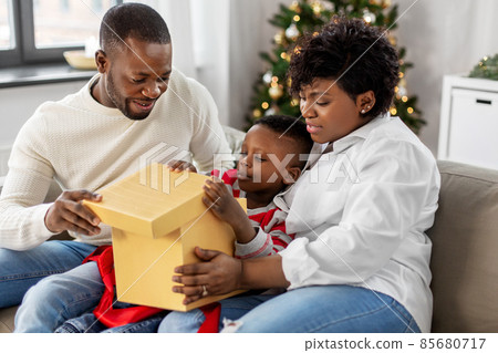 african family opening christmas gift at home 85680717