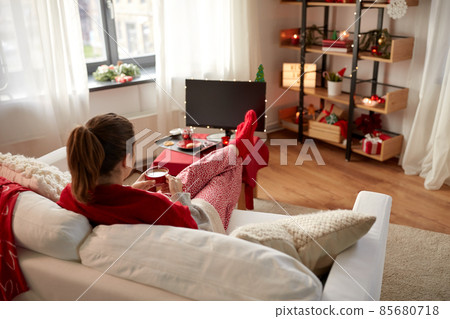 woman watching tv and drinking coffee on christmas 85680718