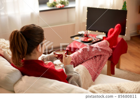 woman watching tv and drinking coffee on christmas 85680811