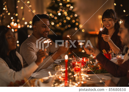 happy friends with sparklers at christmas dinner 85680838