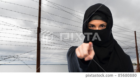 woman in hijab pointing finger over barbed wire woman in hijab pointing finger over barbed wire 85680880