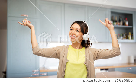 happy woman in headphones dancing on kitchen 85680896