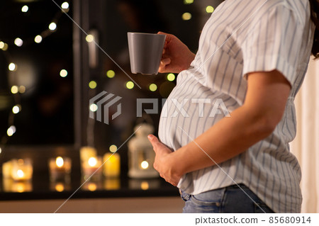 close up of pregnant woman drinking tea at home 85680914