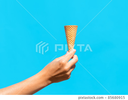close up of hand holding empty ice cream cone 85680915