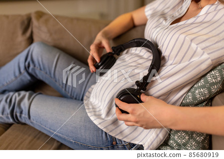 pregnant woman with headphones on her belly 85680919
