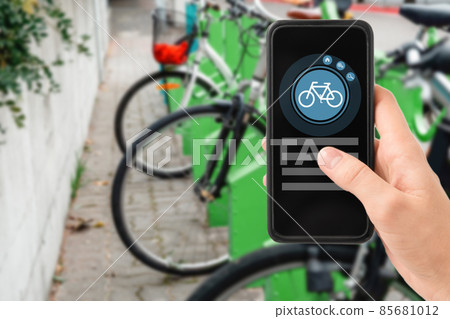 hand with phone at electric bike charging station 85681012