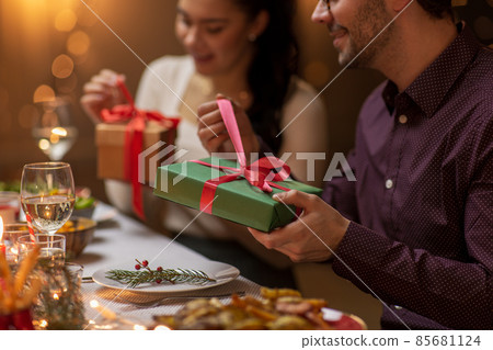 happy people with christmas gifts at dinner party happy people with christmas gifts at dinner party 85681124