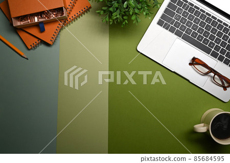 Laptop computer, notebook, glasses, coffee cup and houseplant on green background. 85684595