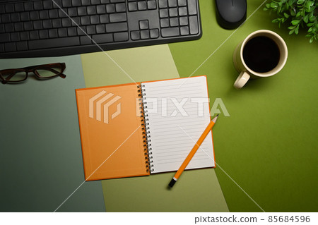 Top view notebook, glasses, coffee cup and houseplant on green background. 85684596