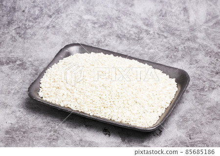 Tray with white rice grains on a gray stone background. Healthy food 85685186