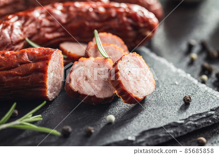 Smoked sausages with pepper, rosemary and garlic on black table. Smoked sausages with pepper, rosemary and garlic on black table. 85685858