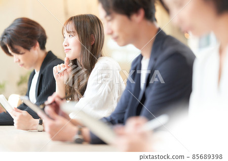 一位年輕女子在參加研討會時在平板電腦上記筆記 85689398