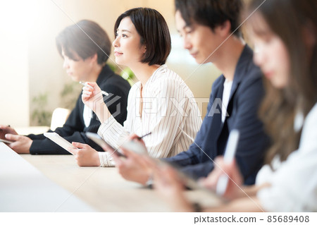 一位年輕女子一邊在平板電腦上做筆記一邊參加研討會 一位年輕女子一邊在平板電腦上做筆記一邊參加研討會 85689408