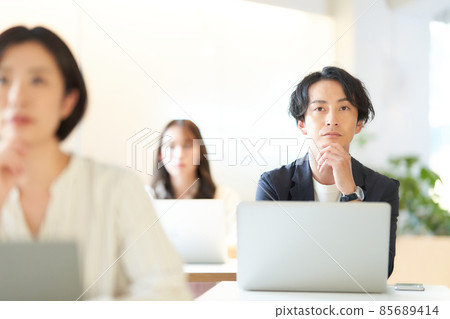 A young man sitting in a classroom and attending a seminar 85689414