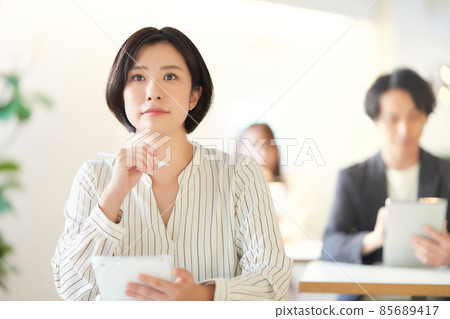 A young woman taking notes on a tablet while taking a seminar A young woman taking notes on a tablet while taking a seminar 85689417