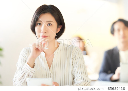 A young woman taking notes on a tablet while taking a seminar 85689418