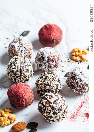 Raw vegan dessert. Energy balls. Truffles made from nuts, seeds, cocoa, dates and superfood powders, white marble background. 85689534