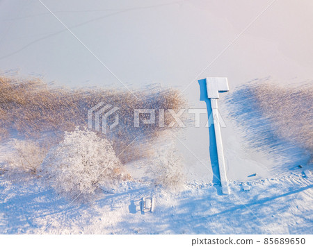 Aerial view of frozen lake and a footbridge covered in snow 85689650