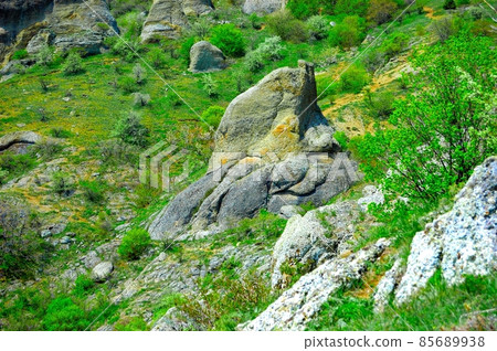 Horizontal background with a magnificent landscape of the Crimean Peninsula. Top view of the mountains covered with lush greenery and the thick clouds below the peaks. Clear blue sky. Copy space. 85689938